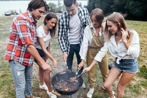 Freunde im Camp kochen ein Grillessen und Würstchen foto