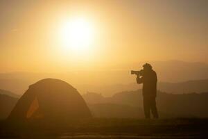 Fotograf ist nehmen Landschaft Foto durch das Zelt während über Nacht Camping beim das schön szenisch Sonnenaufgang Über das Berg zum draussen Abenteuer Ferien Reise