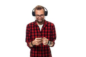jung Hipster Mann im kariert Hemd und Brille tragen Kopfhörer suchen glücklich auf Weiß Hintergrund. foto