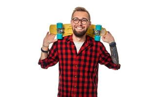 Hipster Mann Über Weiß Hintergrund halten Gelb Skateboard. aktiv Kerl im Plaid Hemd mit Kopieren Raum foto