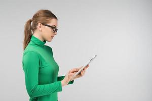 fröhliches Mädchen im Profil arbeitet im Stehen an einem Tablet foto