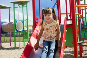 wenig glücklich Mädchen spielen auf das Spielplatz. draussen Spaß foto