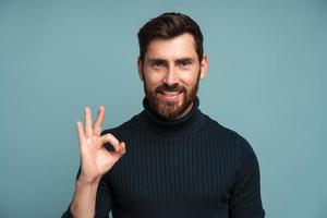 alles ist gut. Zufriedener bärtiger Chef, der eine ok Geste mit den Fingern zeigt, die Arbeit genehmigt, mit der Qualität zufrieden ist. Indoor-Studioaufnahme auf blauem Hintergrund isoliert foto