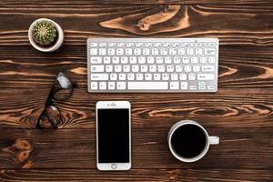 Schreibtisch von oben mit einer Tasse Kaffee und Smartphone foto