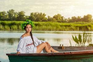 jung sexy Frau auf Boot beim Sonnenuntergang. das Mädchen hat ein Blume Kranz auf ihr Kopf, entspannend und Segeln auf Fluss. Fantasie Kunst Fotografie. foto