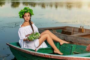 jung sexy Frau auf Boot beim Sonnenuntergang. das Mädchen hat ein Blume Kranz auf ihr Kopf, entspannend und Segeln auf Fluss. Fantasie Kunst Fotografie. foto