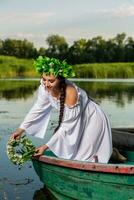 jung sexy Frau auf Boot beim Sonnenuntergang. das Mädchen hat ein Blume Kranz auf ihr Kopf, entspannend und Segeln auf Fluss. Fantasie Kunst Fotografie. foto