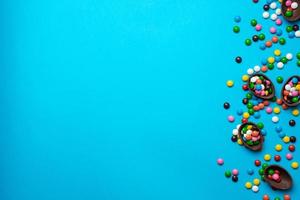 Ostern blauer Hintergrund mit bunten Süßigkeiten in einem Schokoladennest