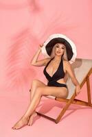 Frau entspannend auf Strand Stuhl. Sonne Bad mit Hut, Sonnenbrille und verschiedene Ausdrücke, Studio Schuss foto