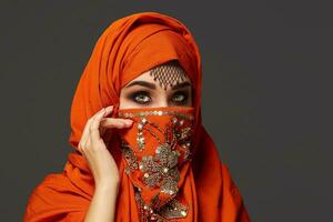 Studio Schuss von ein jung charmant Frau tragen das Terrakotta Hijab dekoriert mit Pailletten und Schmuck. Arabisch Stil. foto