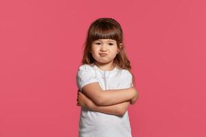 Nahansicht Porträt von ein wenig Brünette Mädchen gekleidet im ein Weiß T-Shirt posieren gegen ein Rosa Studio Hintergrund. aufrichtig Emotionen Konzept. foto
