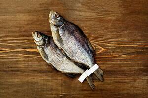 zwei gesalzen zuckte Plötze Fisch mit Etiketten auf Schwänze auf hölzern Hintergrund foto