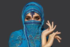 Studio Schuss von ein jung schön Frau tragen das Blau Hijab dekoriert mit Pailletten und Schmuck. Arabisch Stil. foto