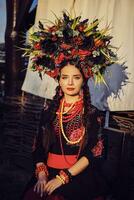 Brünette Mädchen im ein Weiß ukrainisch authentisch National Kostüm und ein Kranz von Blumen ist posieren gegen ein Terrasse. Nahansicht. foto