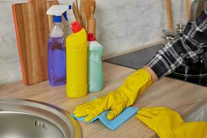 Hände im Handschuhe mit Grün Lappen ist Reinigung Küche Schränke - - Hausarbeit und Hauswirtschaft Konzept foto