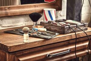 Friseur Werkzeuge auf hölzern Hintergrund. oben Aussicht auf hölzern Tabelle mit Schere, Kamm, Haarbürsten und Haar Klammern, Trimmer. foto