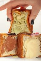 weiblich Hand nehmen geschnitten frisch Sanft Würfel geformt Croissant mit Pistazie Pudding foto