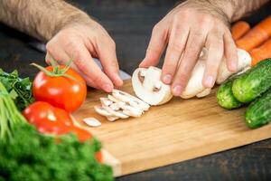 männlich Hände Schneiden Gemüse zum Salat foto