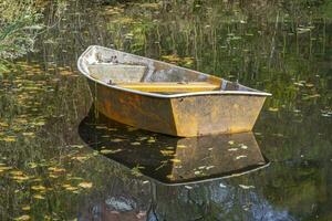 diese Fotos zeigt an ein Boot auf ein klein Teich mit Reflexionen im ein Bauern Dorf im Deutschland