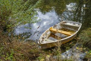 diese Fotos zeigt an ein Boot auf ein klein Teich mit Reflexionen im ein Bauern Dorf im Deutschland