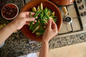 Aussicht von über von Hausfrau Hände Putten frisch organisch Grün Bohnen auf das Tajine während Kochen Abendessen im das Küche foto