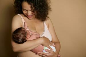 glücklich Mutter hält ihr Neu geboren Baby, Stehen nackt Über Beige Studio Hintergrund, zeigen ihr postnatal Körper mit Mängel foto