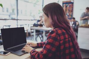 zurück Aussicht von ein jung Rosa Haar Frau Tastatur auf Laptop Computer foto