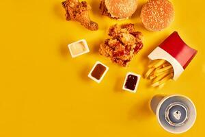 schnell Essen Gericht oben Sicht. Französisch Fritten, Hamburger, Mayonnaise und Ketchup Saucen auf Gelb Hintergrund. foto