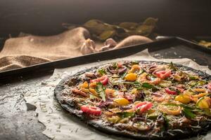 Italienisch Pizza mit schwarz Teig und Meeresfrüchte auf ein Backen Tablett von das Ofen foto