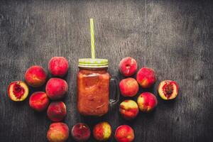 Pfirsich Obst Smoothie im Glas Flasche und Strohhalme auf hölzern Tisch. gesund Lebensstil. getönt foto