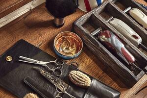 Friseur Werkzeuge auf hölzern Hintergrund. oben Aussicht auf hölzern Tabelle mit Schere, Kamm, Haarbürsten und Haar Klammern, Trimmer. foto