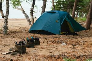 Wandern Tourismus Abenteuer. Camping Picknick Blau Zelt Campingplatz im draussen Wandern Wald. touristisch Stiefel in der Nähe von Camping Zelt. Campingplatz im Natur beim Sommer- Ausflug Lager. Trekking Reise Ferien Konzept. foto