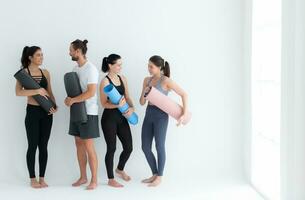 ein Gruppe von weiblich und männlich Sportler stand auf und geplaudert friedlich im das Studio Vor Anfang mit das Yoga Klasse. foto