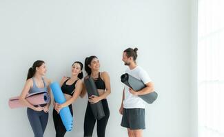 ein Gruppe von weiblich und männlich Sportler stand auf und geplaudert friedlich im das Studio Vor Anfang mit das Yoga Klasse. foto