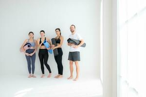 ein Gruppe von weiblich und männlich Sportler stand auf und geplaudert friedlich im das Studio Vor Anfang mit das Yoga Klasse. foto