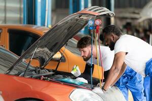 Auto Mechaniker Arbeiten im ein Auto Reparatur Geschäft, inspizieren das Betrieb von das Autos Luft Conditioner und Kältemittel. foto