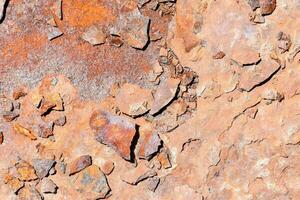 rostig Metall Mauer mit ein wenige Kieselsteine und Felsen foto