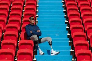 deaktiviert Sportler im ein Blau Hemd Sitzung auf das rot Sitze beim das Stadion, bereiten zum Laufen Ausbildung. foto