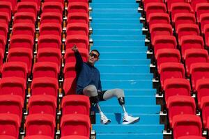 deaktiviert Sportler im ein Blau Hemd Sitzung auf das rot Sitze beim das Stadion, bereiten zum Laufen Ausbildung. foto