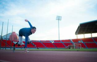 deaktiviert Sportler bereiten im beginnend Position bereit zu Lauf auf Stadion Spur foto