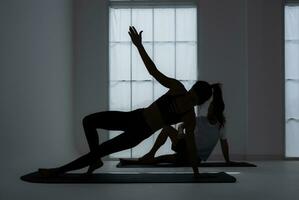 Silhouette von ein jung Paar üben Yoga im das Zimmer. foto