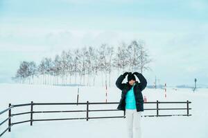Frau Tourist Besuch im Biei, Reisender im Sweatshirt Besichtigung Aussicht mit Schnee im Winter Jahreszeit. Wahrzeichen und Beliebt zum Sehenswürdigkeiten im Hokkaido, Japan. Reise und Ferien Konzept foto