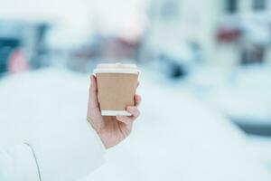 Frau Tourist halten heiß Kaffee oder Tee Papier Tasse mit Schnee im Winter Jahreszeit während Reise im Niseko. Wahrzeichen und Beliebt zum Sehenswürdigkeiten im Hokkaido, Japan. Reise und Ferien Konzepte foto