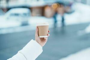 Frau Tourist halten heiß Kaffee oder Tee Papier Tasse mit Schnee im Winter Jahreszeit während Reise im Niseko. Wahrzeichen und Beliebt zum Sehenswürdigkeiten im Hokkaido, Japan. Reise und Ferien Konzepte foto
