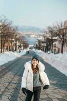 Frau Tourist Besuch im Hakodate, Reisender im Sweatshirt Besichtigung hachiman zaka Steigung mit Schnee im Winter. Wahrzeichen und Beliebt zum Sehenswürdigkeiten im Hokkaido, Japan. Reise und Ferien Konzept foto
