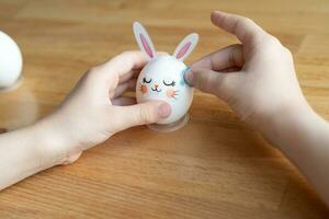 Kind Hände schmücken Ostern Ei im bilden von Hase. vorbereiten zum Ostern Konzept. selektiv Fokus foto
