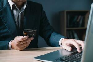 Geschäftsmann Verwendet ein Computer Laptop und Anerkennung Karte zu Kaufen oder Kauf produzieren Zahlung online und sitzt auf das Stuhl im das Leben Zimmer beim heim. das Konzept von Finanzen und online Einkaufen. foto