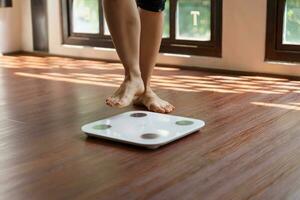 Fett Diät und Rahmen Füße Stehen auf elektronisch Waage zum Gewicht Kontrolle. Messung Instrument im Kilogramm zum ein Diät Steuerung foto