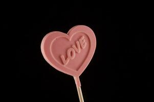 ein Rosa Herz geformt Lutscher mit das Wort Liebe geschrieben auf es foto