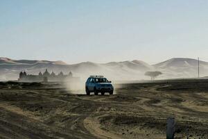 ein Fahrzeug Fahren durch das Wüste mit Sand Dünen im das Hintergrund foto